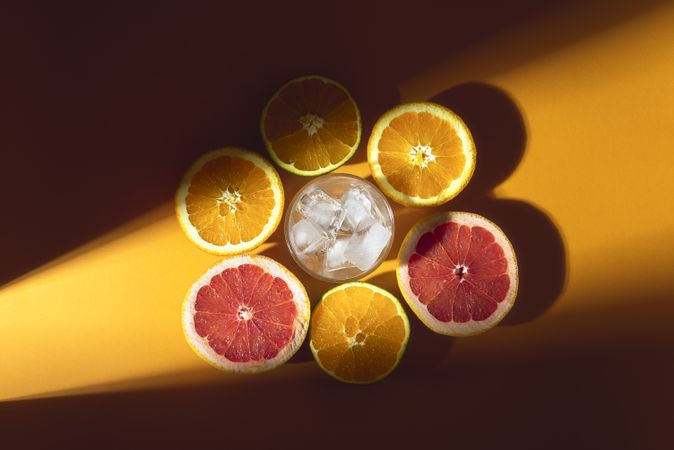 Citrus fruits and glass of ice in sunlight