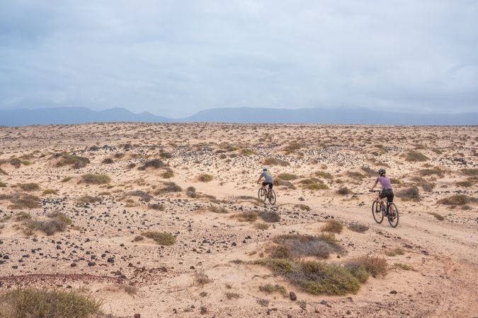 Side of man and woman biking on rugged terrain