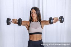 Young woman doing arm exercises using dumbbells 5zpDob