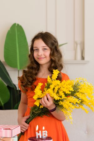 Girl in an orange dress holding yellow flowers
