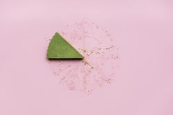 Last slice of matcha cheesecake on pink table