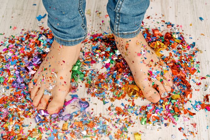 Boy standing on bright confetti scattered on floor