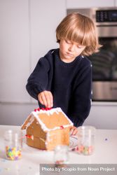 Boy making gingerbread house in the kitchen 4AAe84