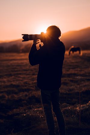 Man shooting on camera beautiful landscape between hills
