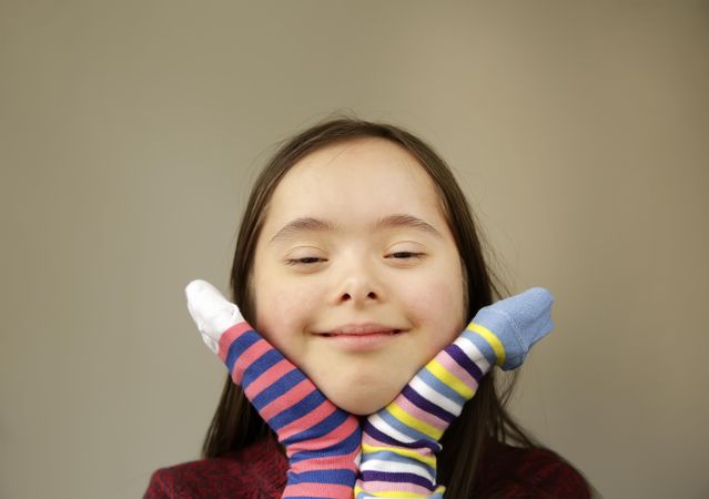 Close up of young girl smiling and wearing socks on her hands