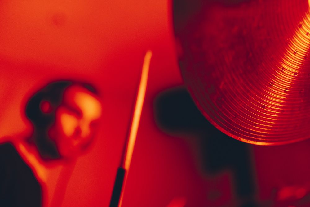 Man with drumsticks playing on drums in redness