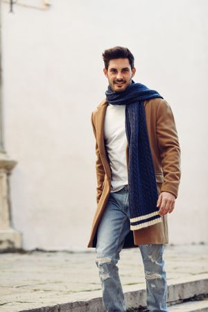 Smiling man wearing winter clothes in the street with jeans