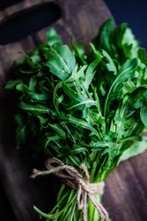 Close up of bunch of arugula on wooden board