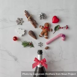 Champagne bottle with festive decorations; ribbons, candy cane, gingerbread, on marble background bEyklb