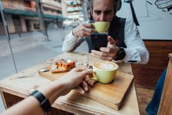 Two people with cappuccinos and dessert in cafe