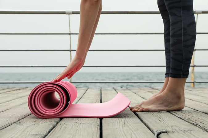 Yoga mat, female hands and feet on wooden floor at sea