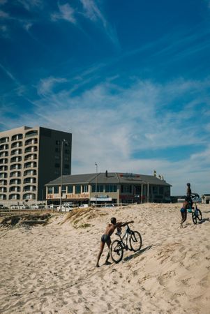 Two boys pushing bikes in the sand