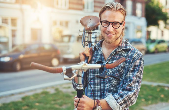 Man in glasses carrying his bicycle on his shoulder