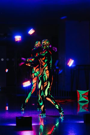 Two people with neon body paint performing on stage