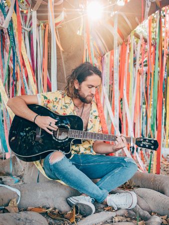 Man sitting under tree playing guitar