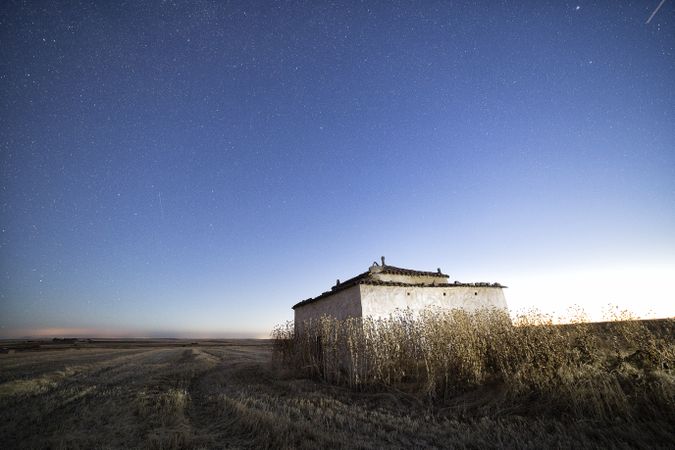 Aged house in rural countryside under starry sky
