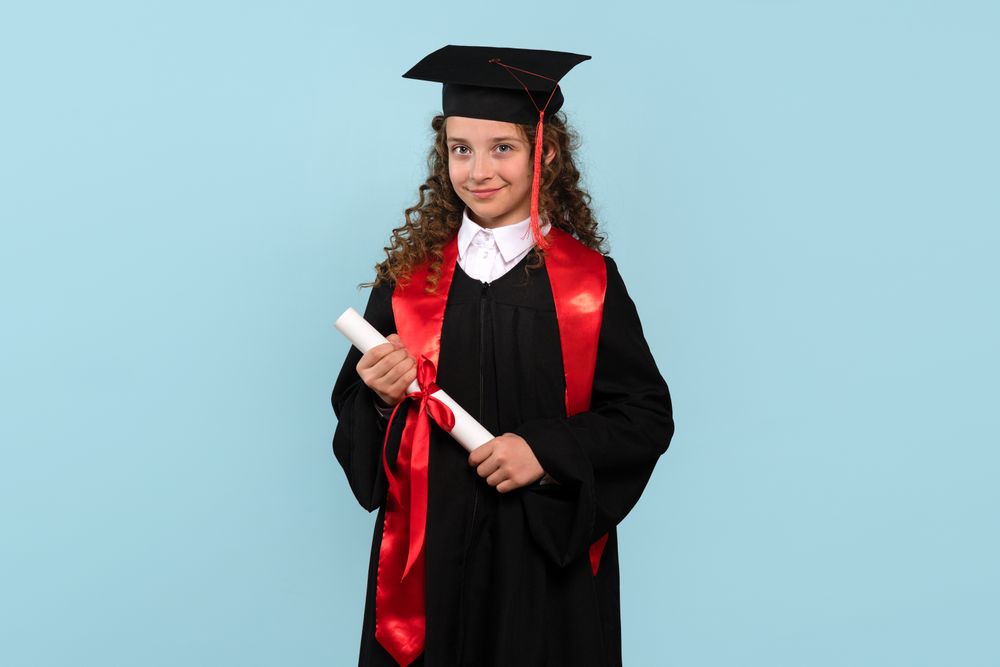 Young girl in graduation attire holding diploma and smiling confidently.