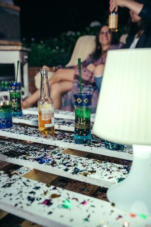 Lamp & drinks over pallets table with confetti in outdoors party