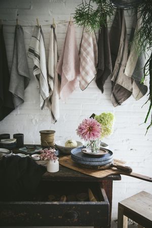 Table with flowers in vase on trays near towels hanging on thread