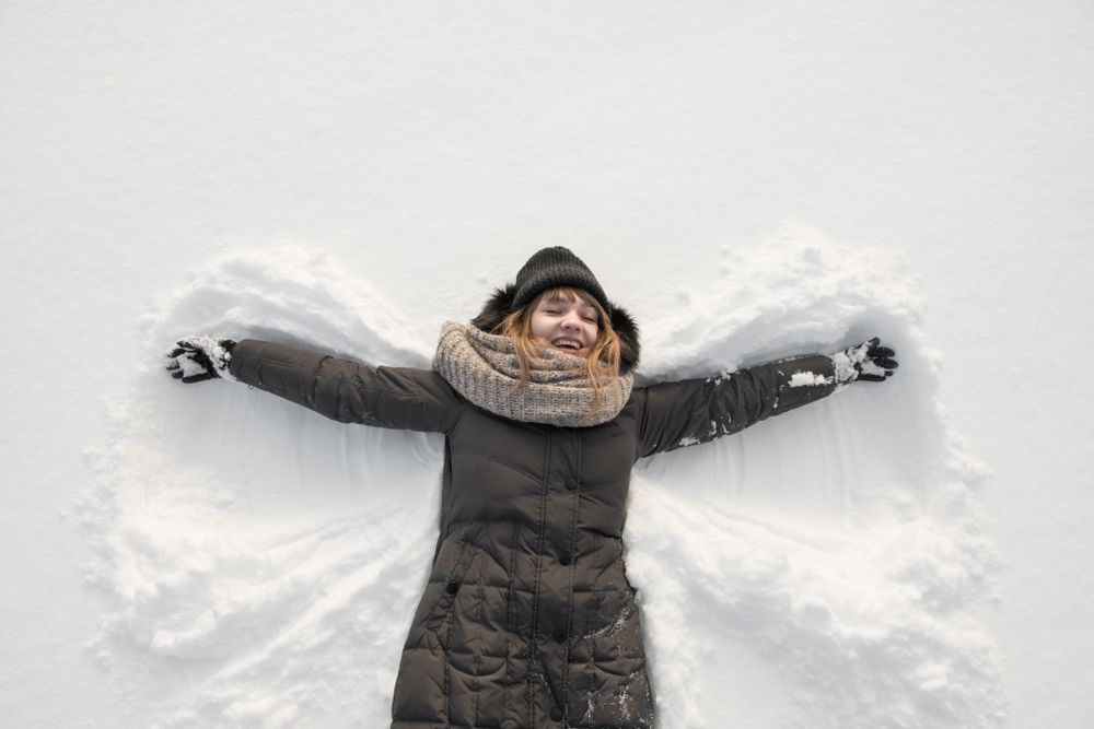 Woman in winter wear making snow angel