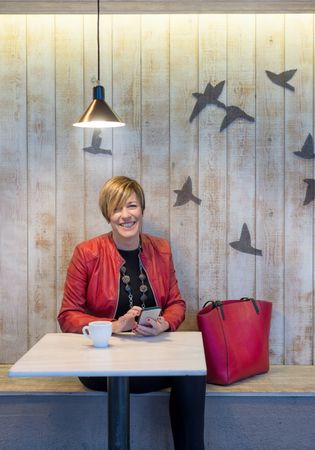 Business woman dressed in red holding phone in restaurant