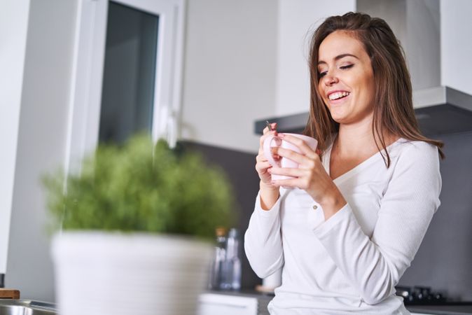 Woman drinking from cup in kitchen