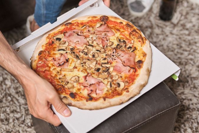 Crop man with takeaway pizza on table