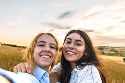 two women selfie on a field at sunset