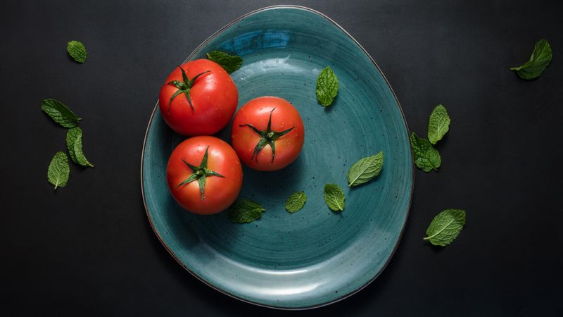 Ripe tomatoes and mint leaves in a plate