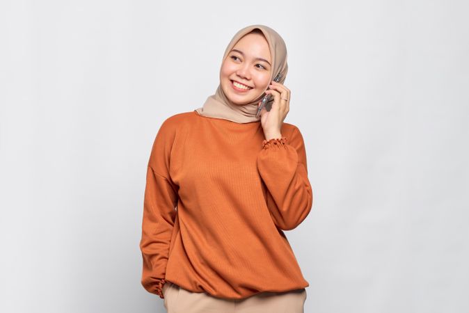 Happy Muslim woman smiling with smart phone to her ear