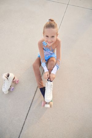 Happy girl putting on roller skate