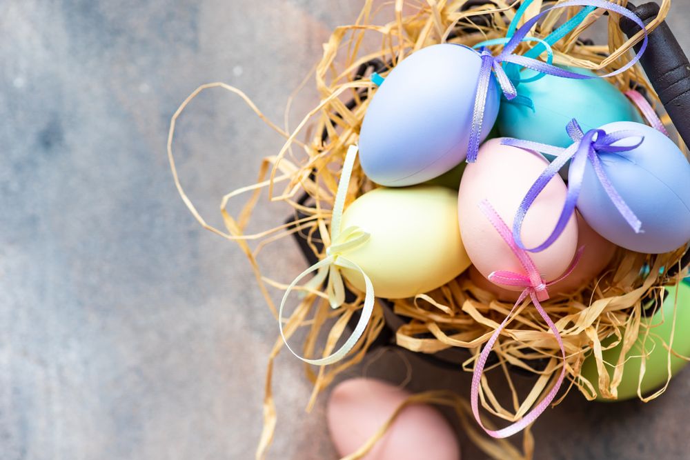 Top view of decorative Easter eggs in straw on table with copy space