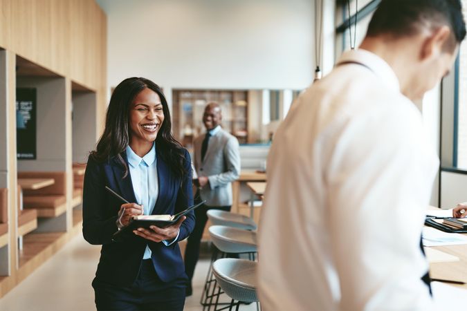 Smiling woman writing notes while standing in office