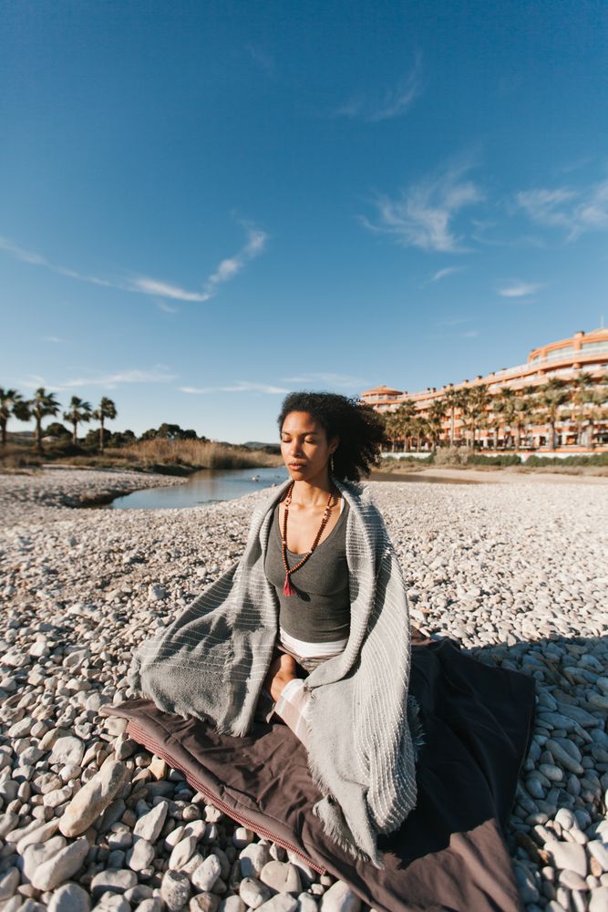 Sportive woman sitting on sandy beach in asana