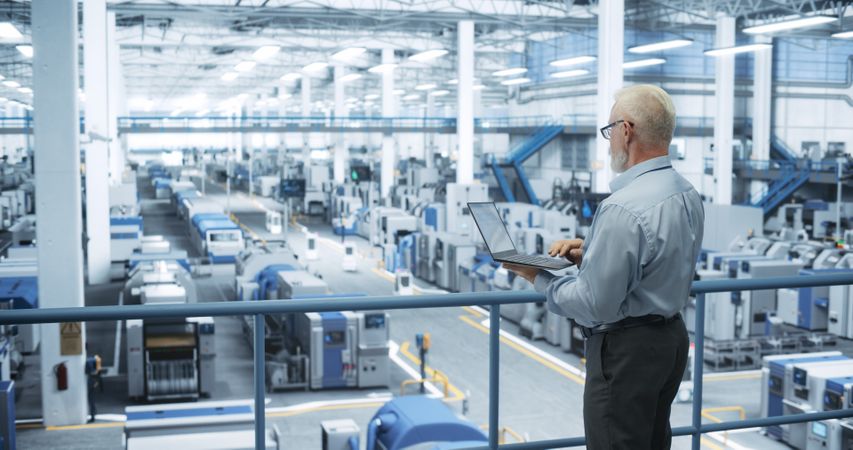 Thoughtful Engineer Monitoring and Analyzing Conditions at a Pristine Modern Electronics Factory with Automated Mobility Robots Working with the Help of Artificial Intelligence Software