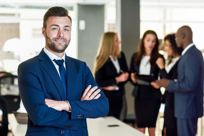 Male professional standing in foreground of busy office