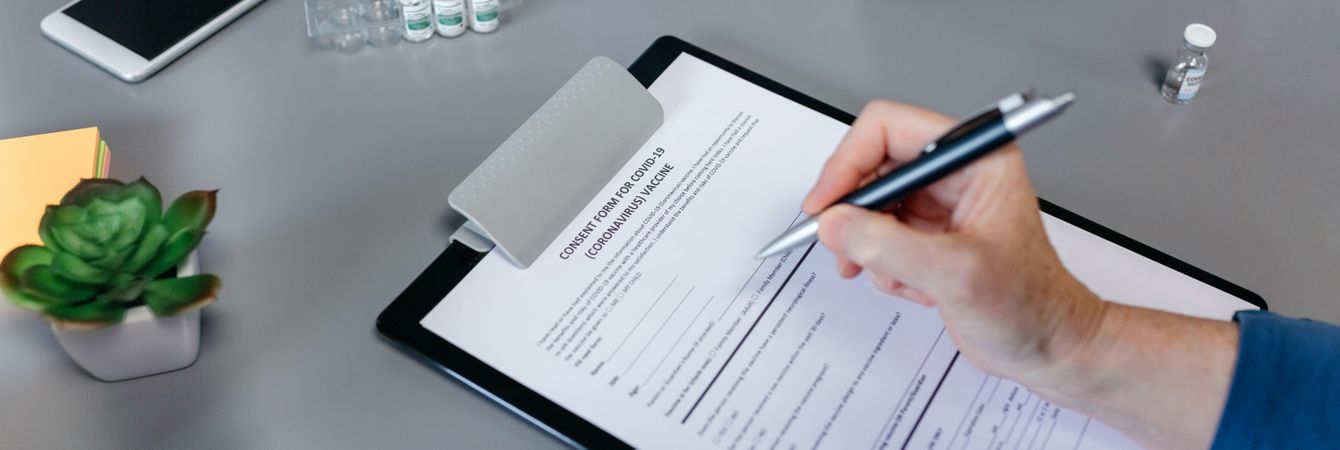 Unrecognizable woman filling in consent form for coronavirus vaccine