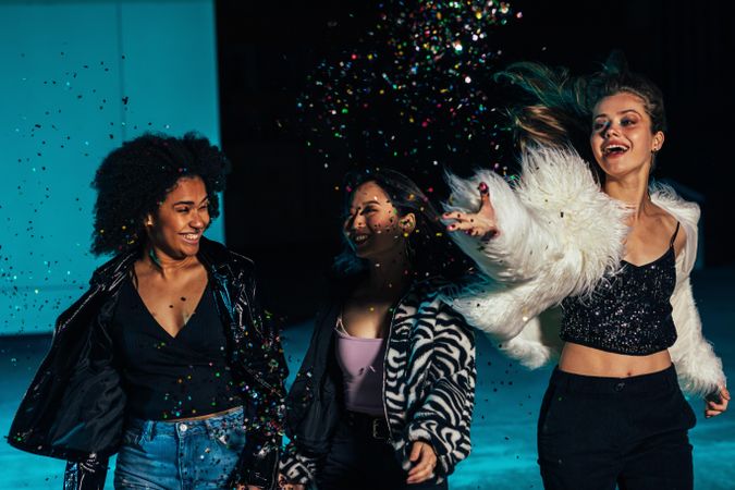 Multi-ethnic group of woman at party with confetti in blue lighting