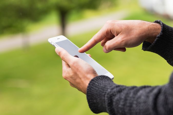 Anonymous man browsing on mobile phone on terrace