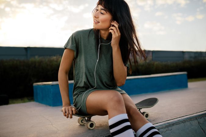 Woman relaxing at skate park listening music