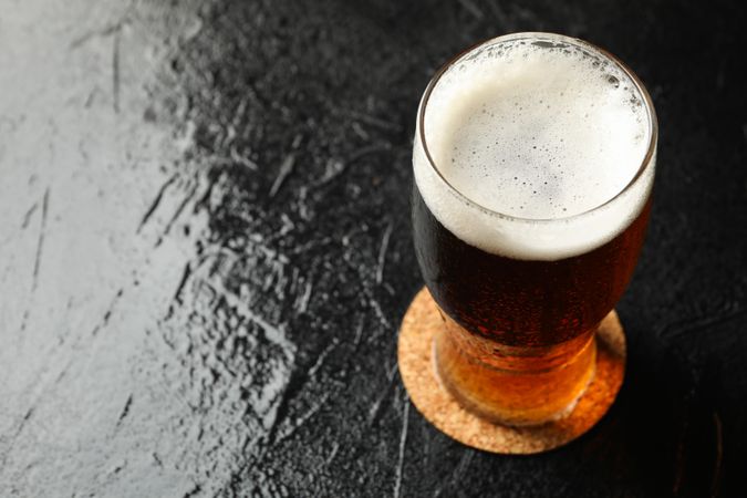 Glass of beer on dark table, close up