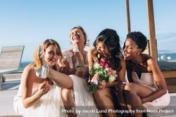 Bride drinking wine while sitting on rooftop with bridesmaids 4d6YL0