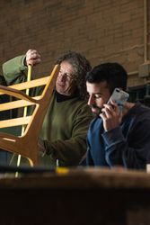 Focused man talking on smartphone and writing notes in carpentry