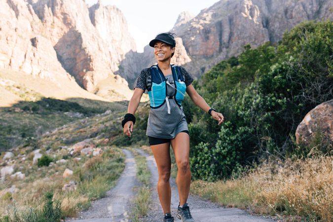 Happy healthy female hiking through trail in a valley