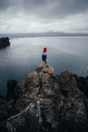 Man standing on edge of cliff on overcast day, portrait