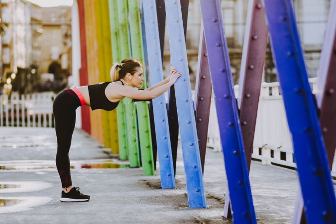 Woman with earphones stretching legs on street