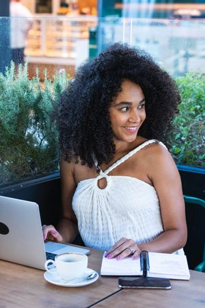 Smiling Black woman working on laptop in cafe