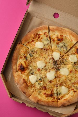Cheese pizza in carton box on violet background