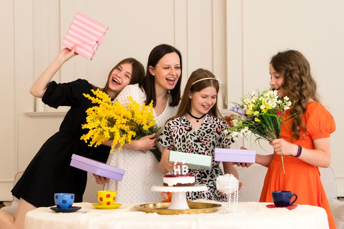 Family celebrating birthday with flowers, gifts and cake