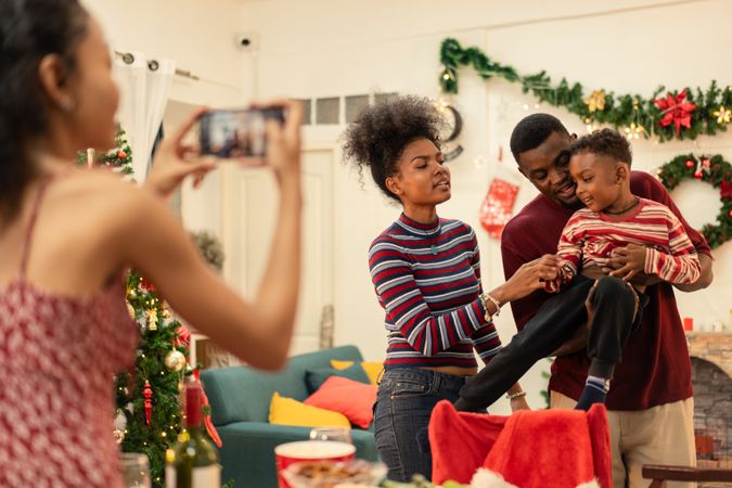 Black woman using smartphone taking picture of a family during Christmas